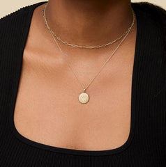 A woman is wearing the Kyle Cavan Gold Washington Sunburst Crest Necklace. Hover